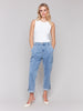 A woman is standing, wearing chambray blue cargo pants with a relaxed fit and functional pockets. She has a sleeveless white top on and light-colored shoes.