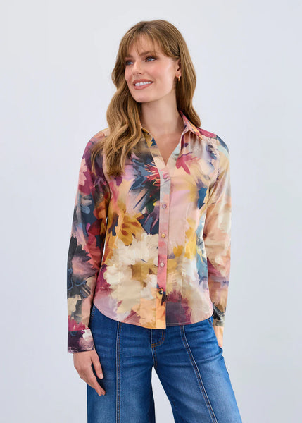 Woman wearing a colorful floral blouse and blue jeans against a white background