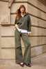 Woman in olive green outfit standing against a stone wall