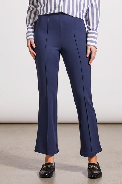 A person wearing a pair of navy blue bootcut trousers and a striped shirt, standing against a neutral background.