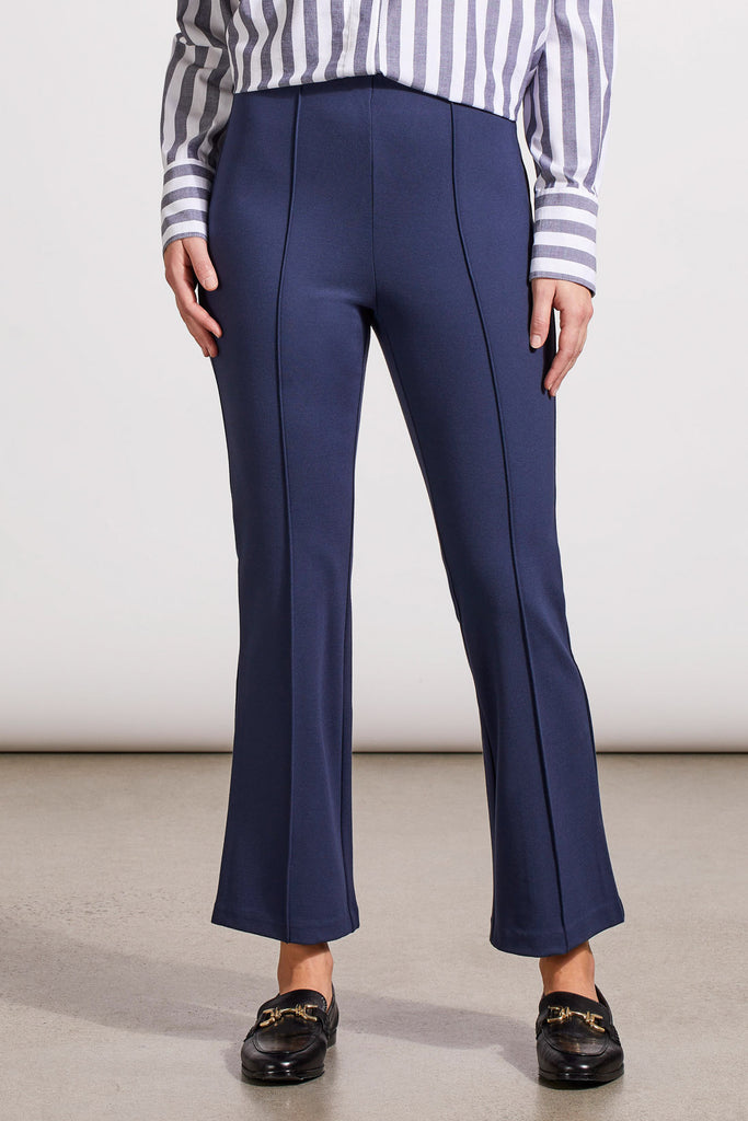 A person wearing a pair of navy blue bootcut trousers and a striped shirt, standing against a neutral background.