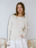 Woman wearing a cream sweater with black trim against a plain background