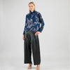 Woman wearing a blue floral blouse and black wide-leg pants on a white background