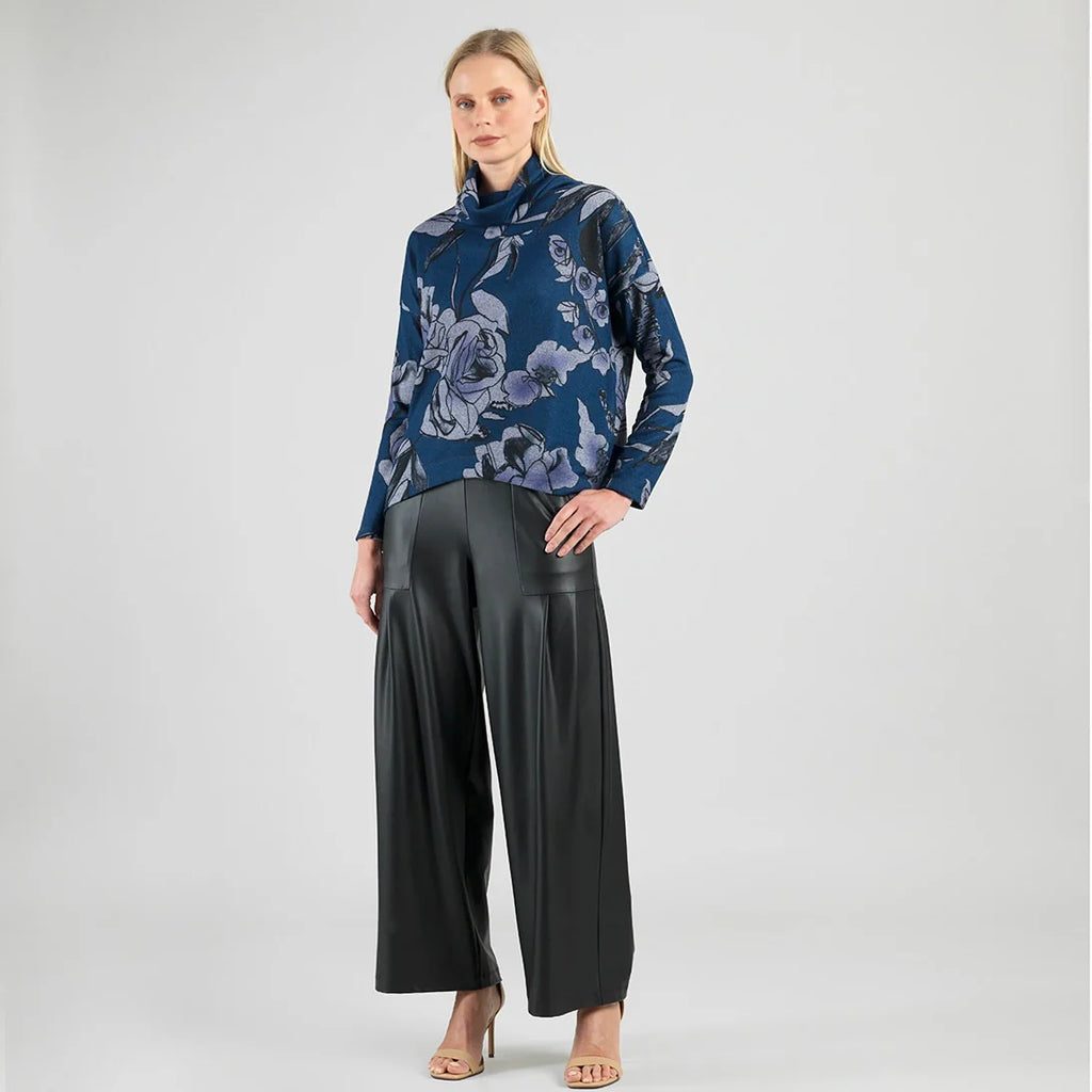 Woman wearing a blue floral blouse and black wide-leg pants on a white background