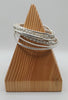 Set of silver bracelets on a wooden stand against a white background