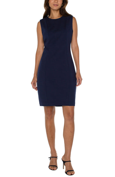 A navy blue sleeveless sheath dress with a round neckline, three-quarter sleeves, and a knee-length skirt.